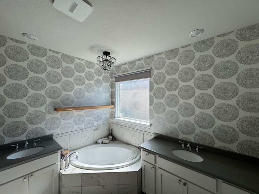 Modern bathroom featuring expert wallpaper installation, wall accent with a jacuzzi, and decorative chandelier
